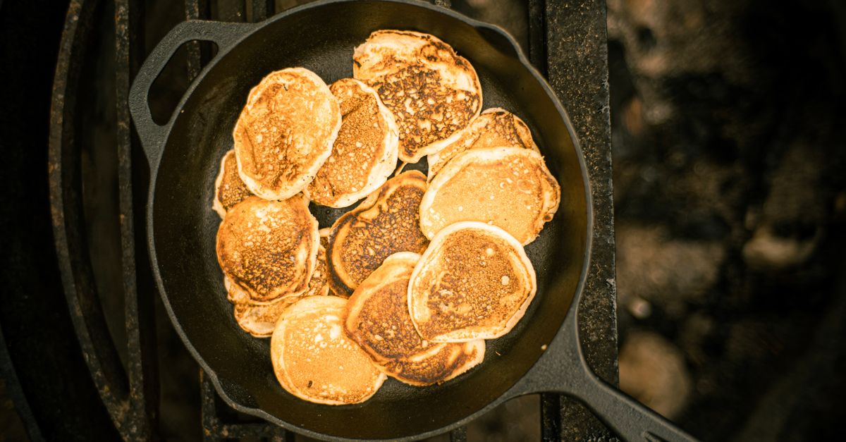 A delicious stack of golden pancakes cooked in a cast iron skillet, photographed from above.